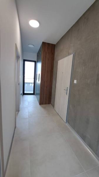 The hallway of a 2-room apartment with doors, light walls, and a cabinet.