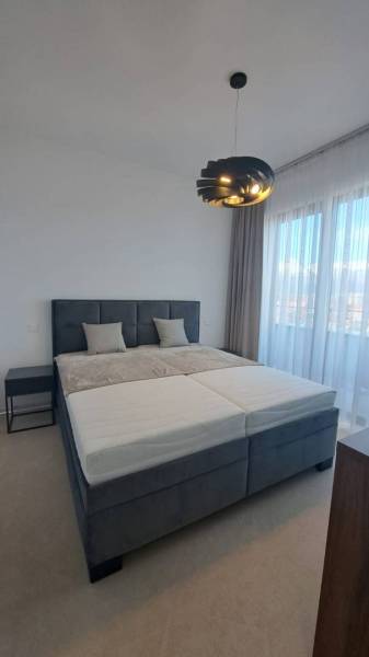 Bedroom with a large bed and a modern lamp in a two-room apartment.