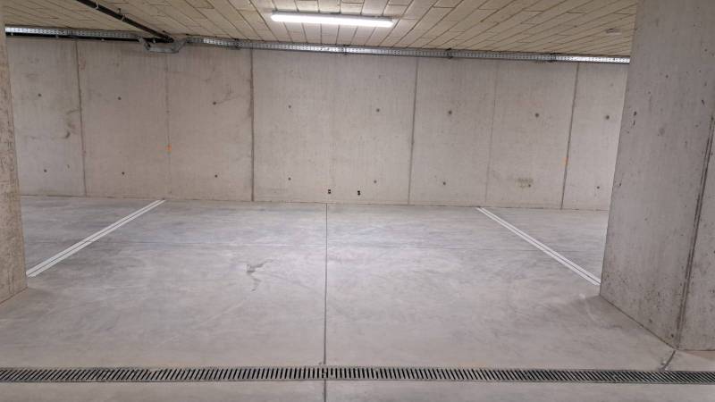 Parking space in an underground garage with concrete walls and floor.