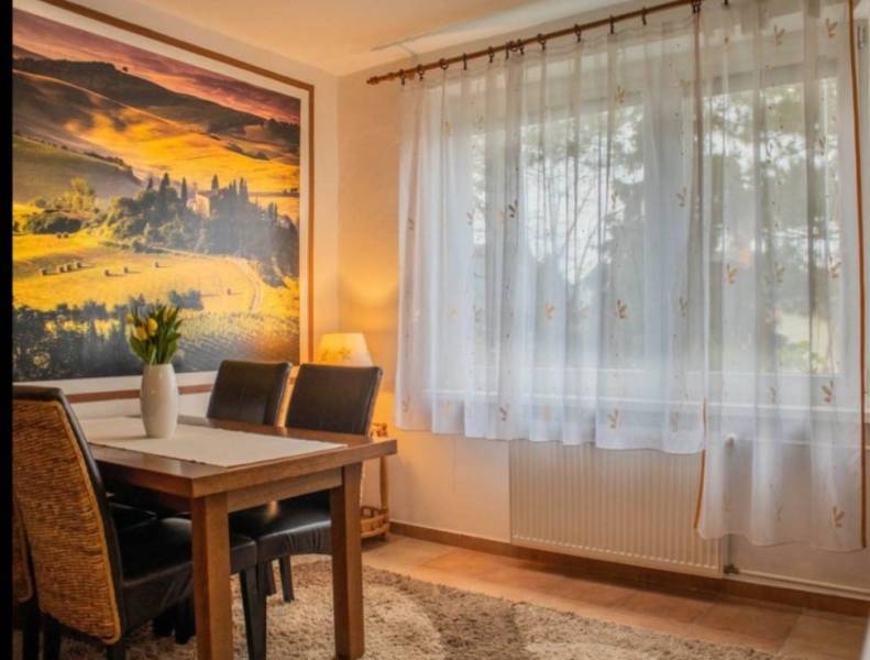 Living room in a studio apartment with a wooden table and picture decor on the wall.