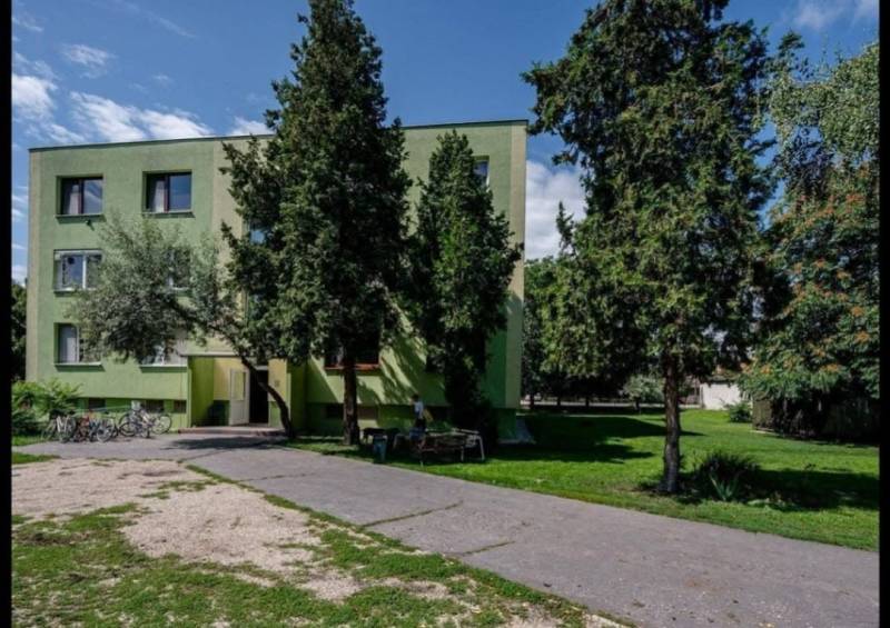 A hut surrounded by trees in Číčov, next to an asphalt road and bicycles.