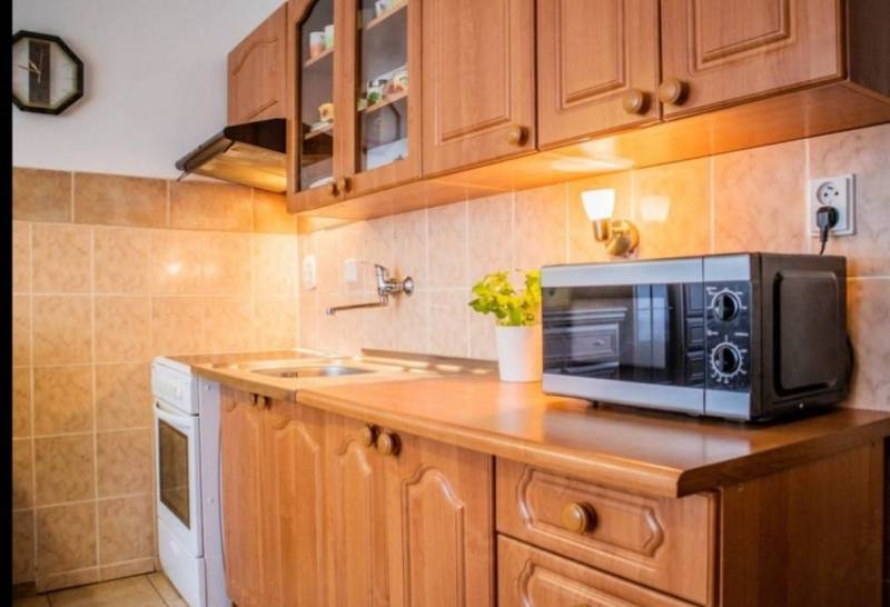 A kitchenette in a studio apartment with a microwave and wooden cabinets.