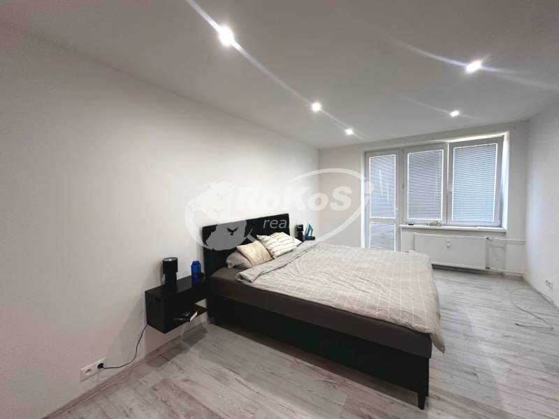 Bedroom in a two-room apartment, with a bed and nightstands, light flooring.