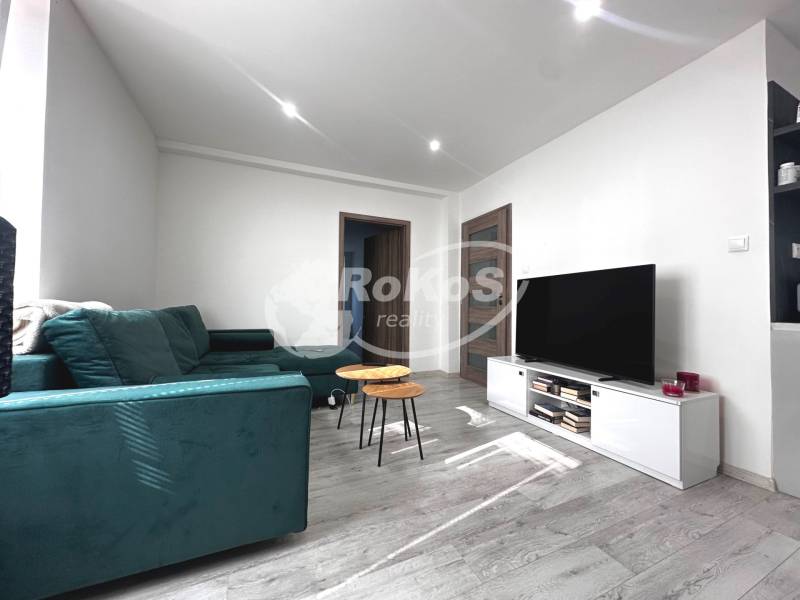 Living room in a 2-room apartment with a sofa, TV, table, and minimalist interior.