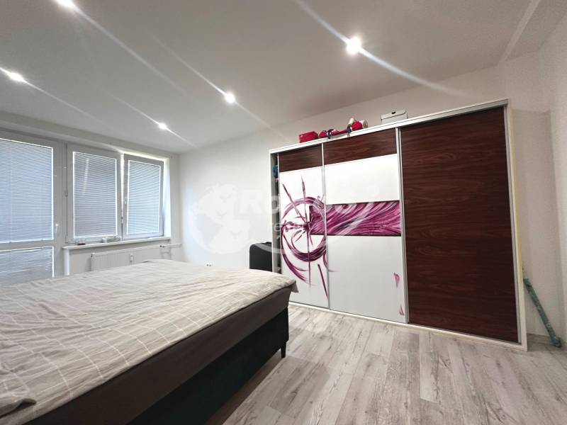 Bedroom with a bed, built-in wardrobe, and windows in a 2-room apartment.