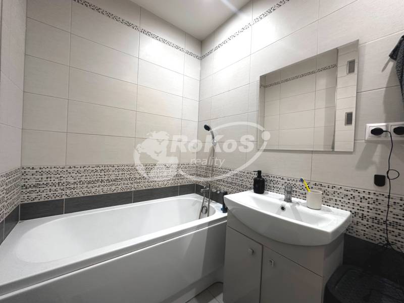 Bathroom in a 2-room apartment with a bathtub, sink, and mirror on the wall.