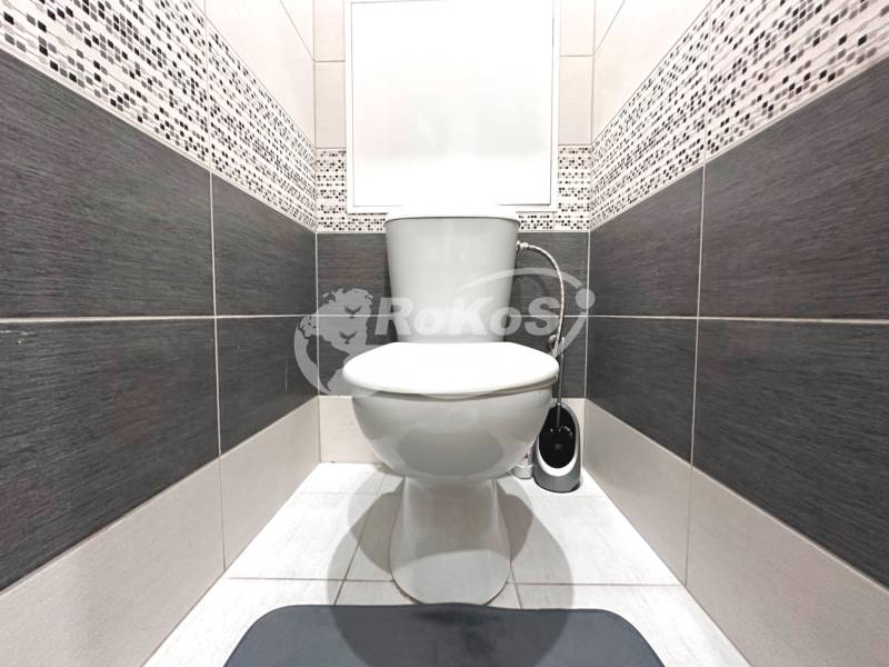 A toilet with ceramic tiles in a 2-room apartment, in black and white tones.