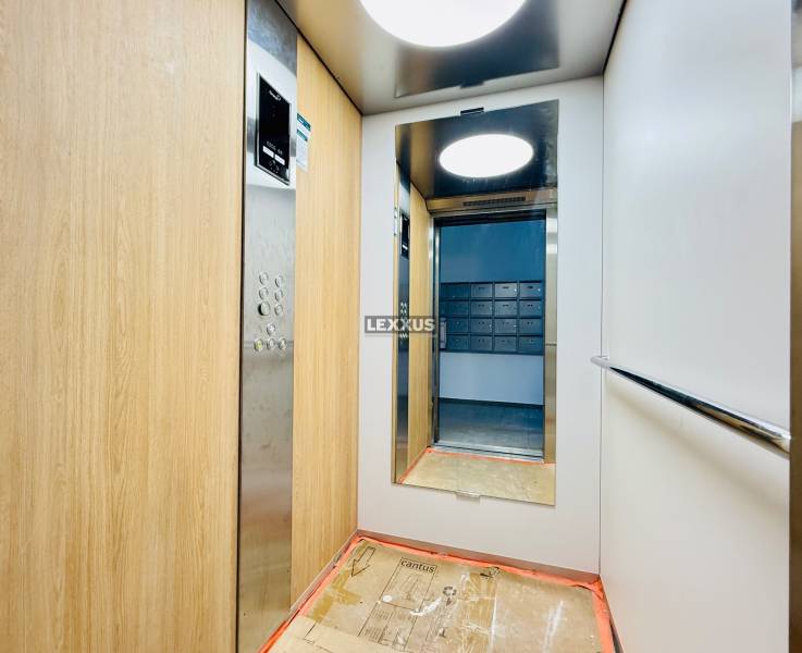 An elevator with wooden paneling and a mirror, view of mailboxes outside.