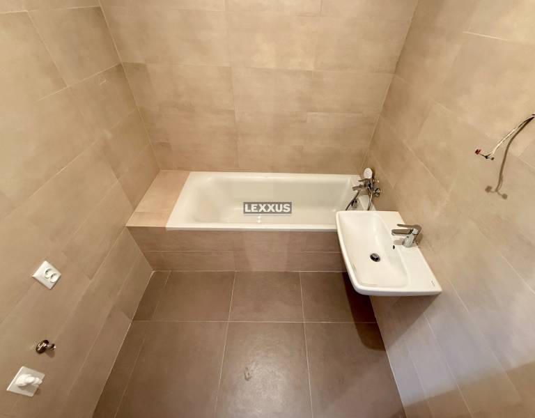 A bathroom in a 2-room apartment with a bathtub and a sink, light tiles.