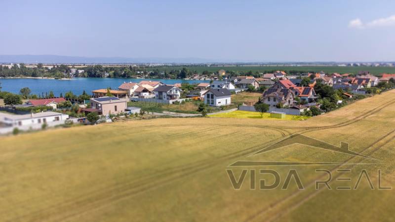 Plots - housing in Dunajská Lužná with a view of the lake, houses, and fields.