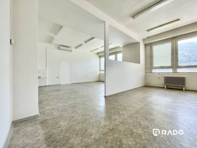 Offices with empty space, white walls, large windows, and a radiator.
