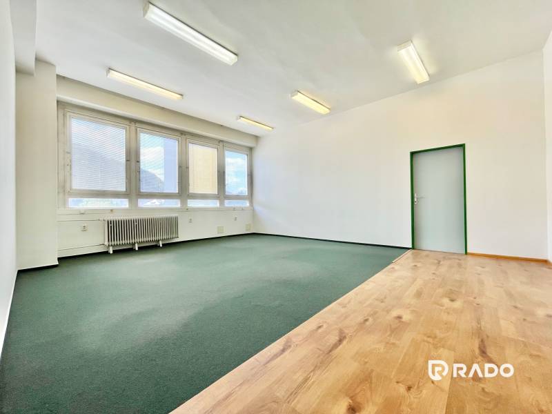 Office interior with windows, parquet floors, and carpets, suitable for a work environment.