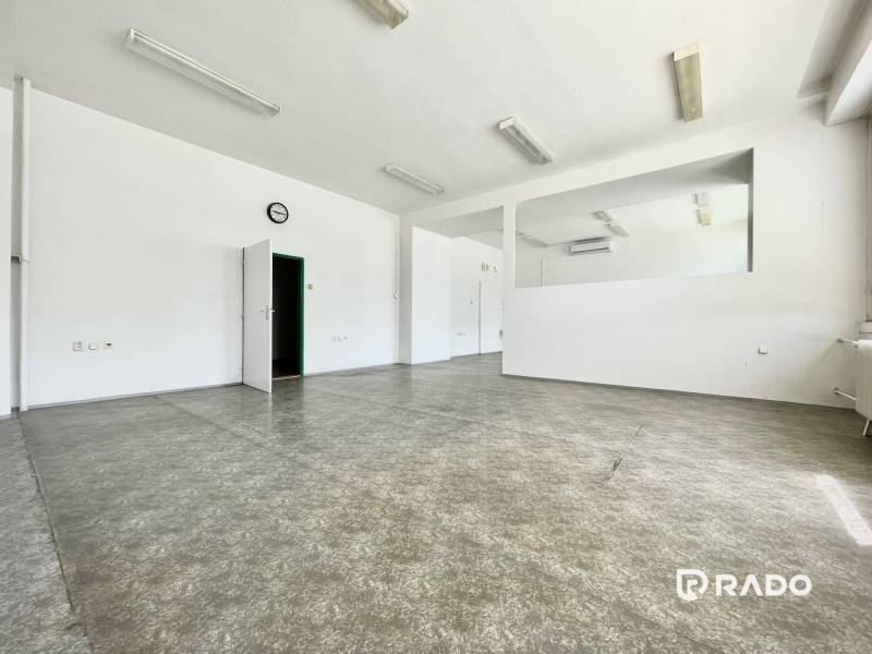 Spacious offices with white walls, tiled floor, doors, clock on the wall.