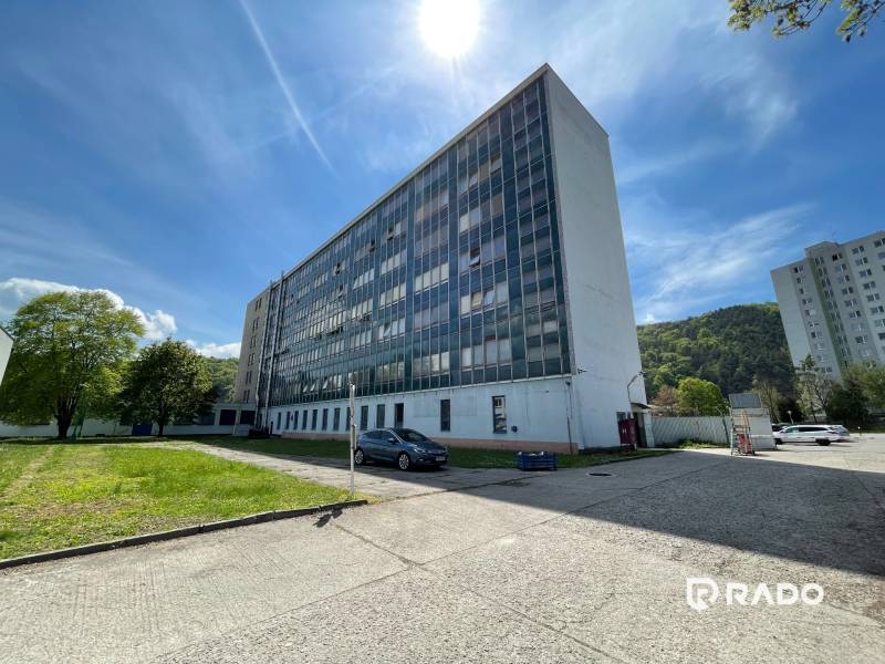Offices on K výstavisku Street in Trenčín, next to it is a lawn and a parked car.