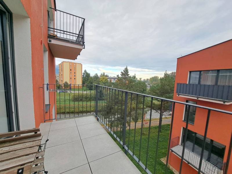 A balcony in a 2-room apartment on Jilemnického Street in the town of Svit with a view of greenery.