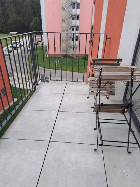 A balcony with a view of Jilemnického Street in the town of Svit; contains wooden furniture.