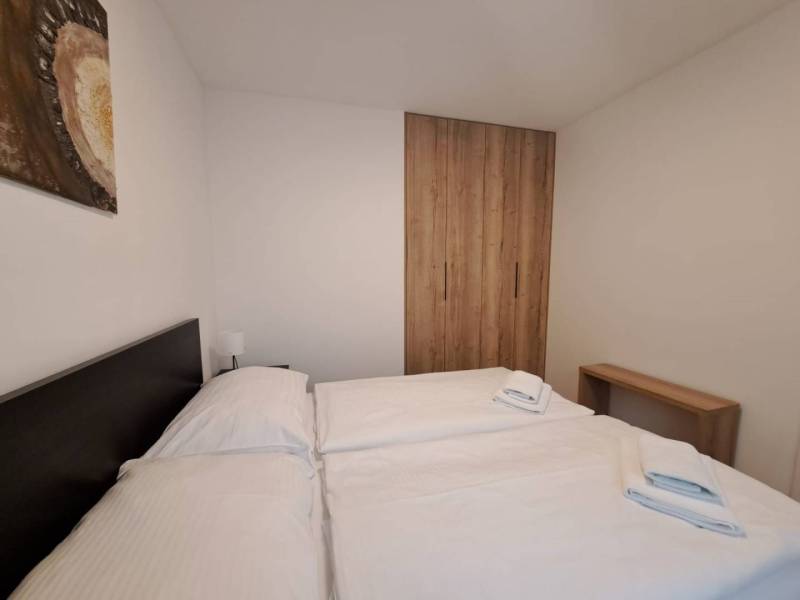 A bedroom in a two-room apartment with a bed, a wooden wardrobe, and a picture on the wall.