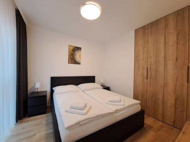 Bedroom with a double bed, tables, and a wardrobe in a 2-room apartment.