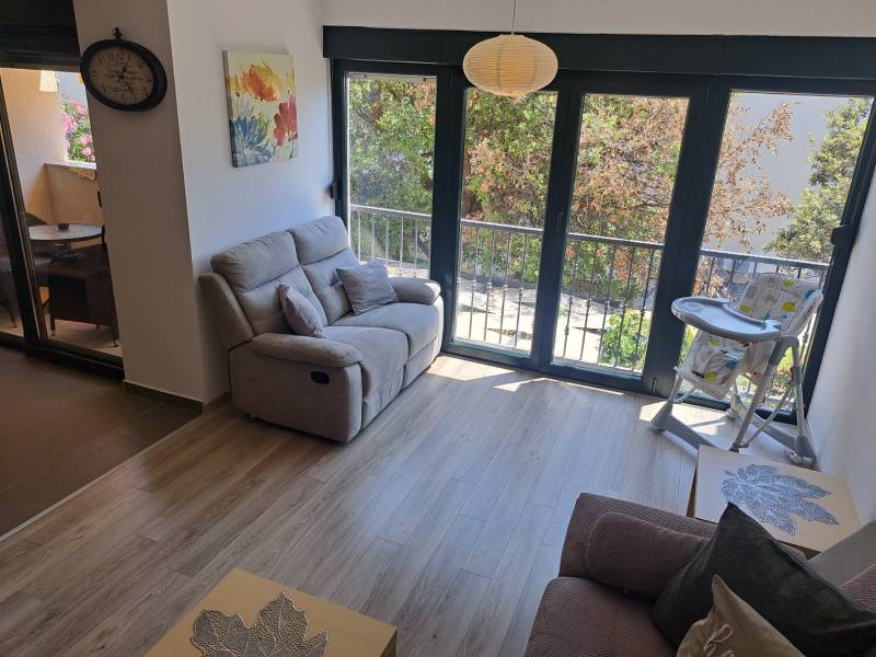 Living room of a three-room apartment with a sofa, balcony, and a high chair for toddlers.