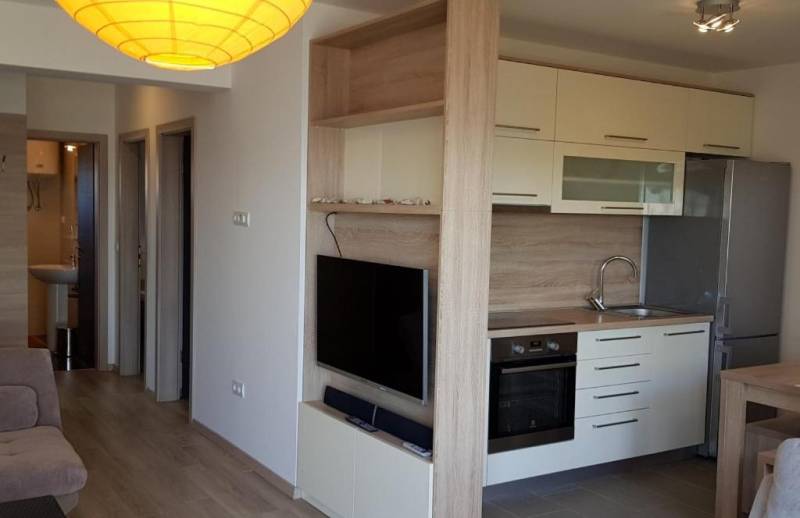 A kitchen in a 3-room apartment with built-in appliances and a TV on the wall.