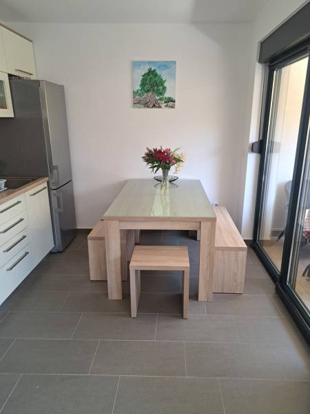 Dining area in a 3-room apartment with a wooden table, flowers, and a painting of a tree on the wall.