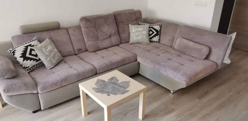 A comfortable sofa set in a 3-room apartment, complemented by cushions and a table with a leaf motif.