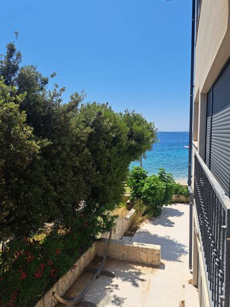 View from a 3-room apartment in Mandre to the sea, framed by greenery and tiles.