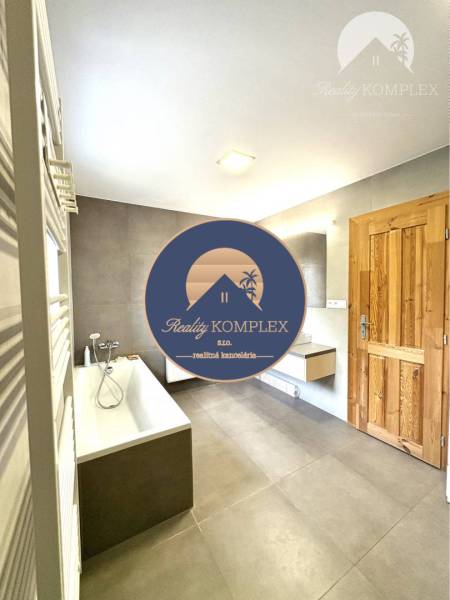 Bathroom in a family house with a bathtub and wooden door.