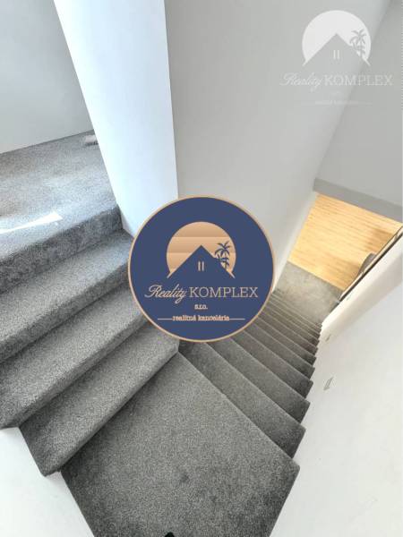 Interior of a family house with a staircase covered in carpet and a wooden floor below.