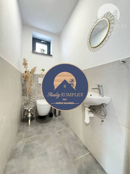 A toilet in a family house with a window, a mirror, and a decorative stool.