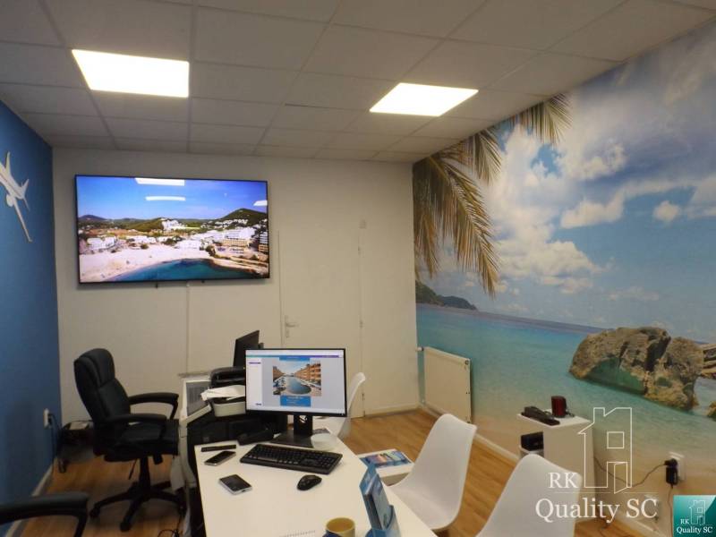An office with a computer and a tropical beach decoration on the wall in a building.