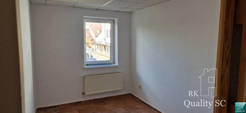 A room with a window, a radiator, and white walls in a building.