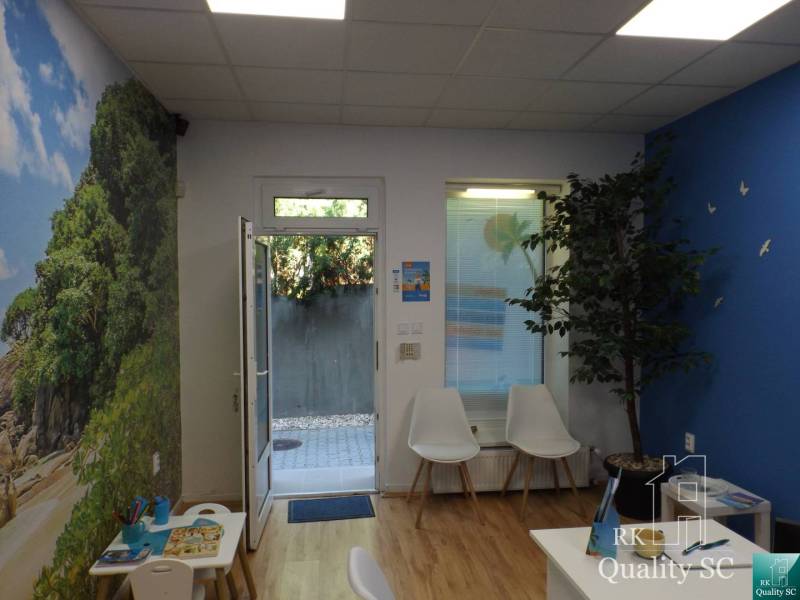 Interior of a building with a children's corner and a plant, light walls, open doors.