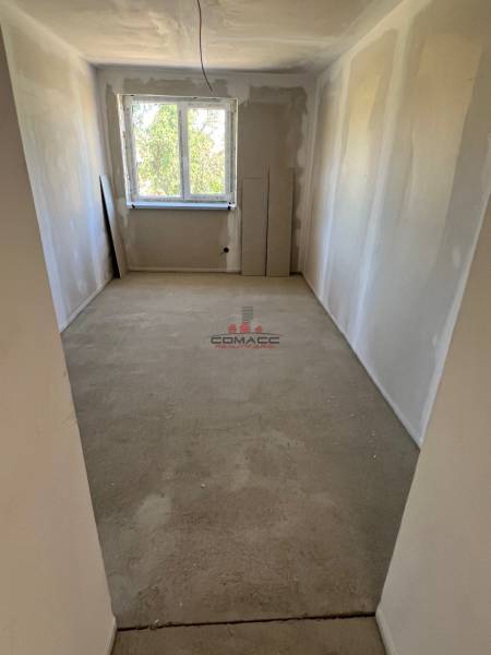 An empty room with a window, white walls without flooring in a family house.