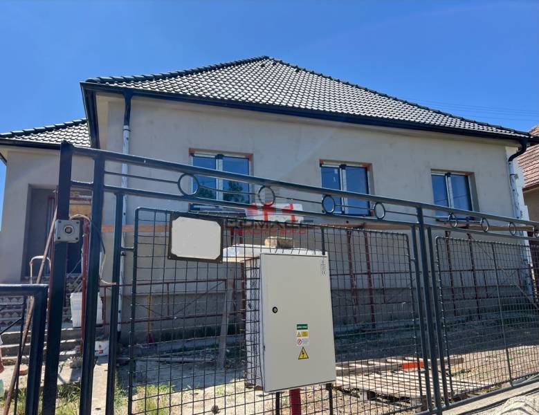 A family house in Sasinkovo on Sasinkovo Street with an unfinished facade behind a metal fence.
