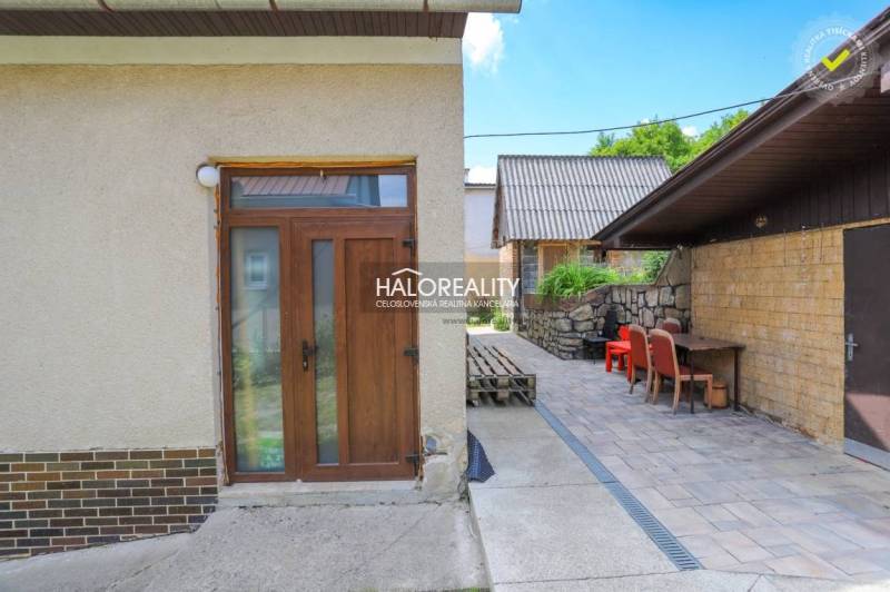 A family house in Dolná Mariková with a terrace, stone wall, and garden furniture.