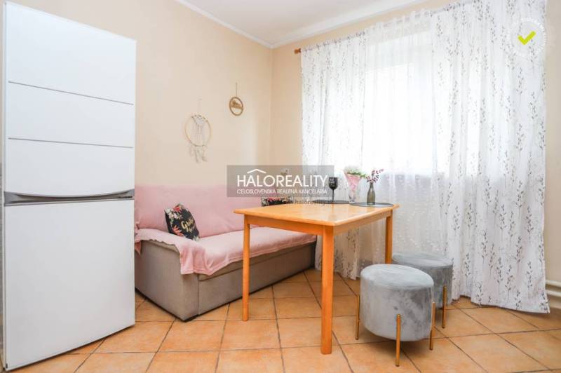 Dining area in a family house with a sofa, table, and light curtains.