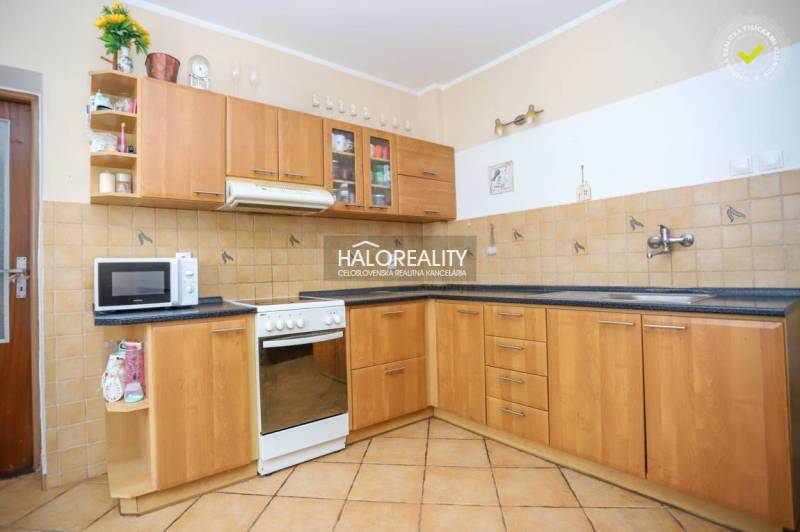 A kitchen in a family house with wooden cabinets and light tiles.
