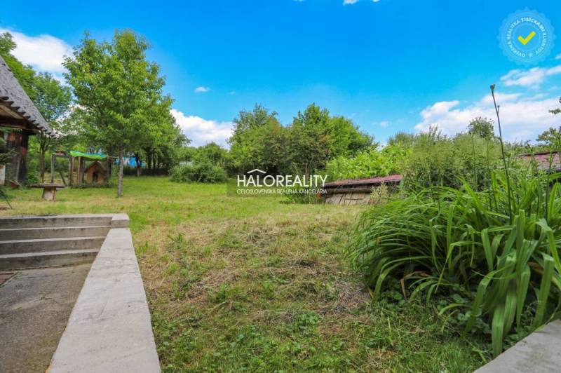 The garden of the family house in Dolná Mariková is surrounded by trees and a grassy area.