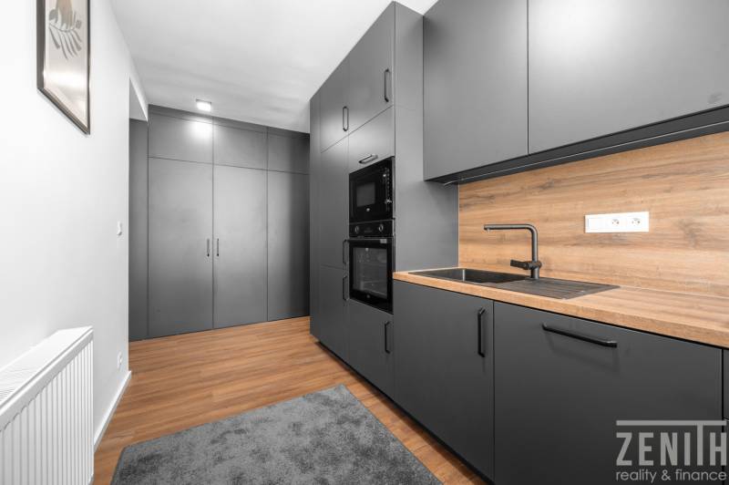 A kitchen with black cabinets and a wooden countertop in a 3-room apartment.
