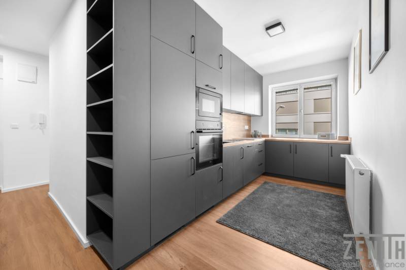 A kitchen in a 3-room apartment with gray cabinets and a wooden floor.