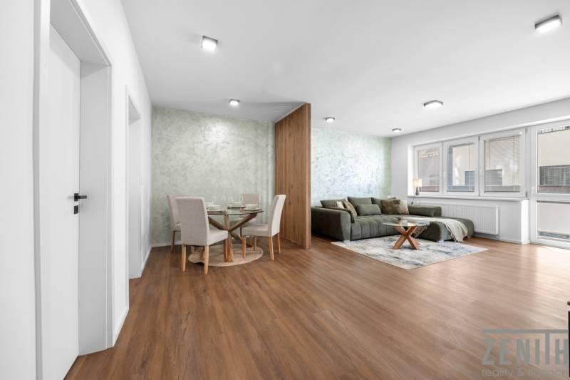 Living room in a three-room apartment with wooden flooring, a sofa, and a dining table.