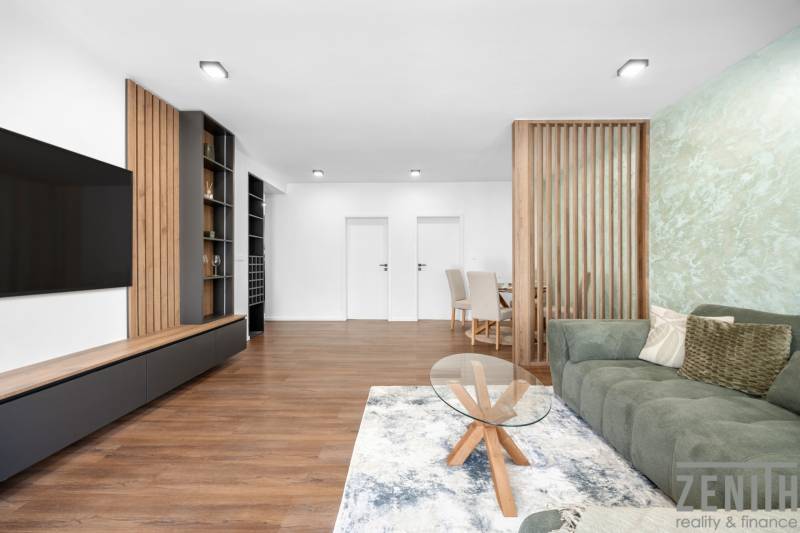 Living room with an area rug and a green sofa in a three-room apartment.
