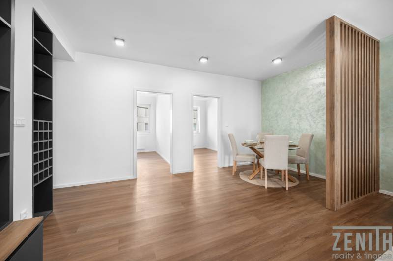 Dining area in a 3-room apartment with wooden flooring and a green wall.