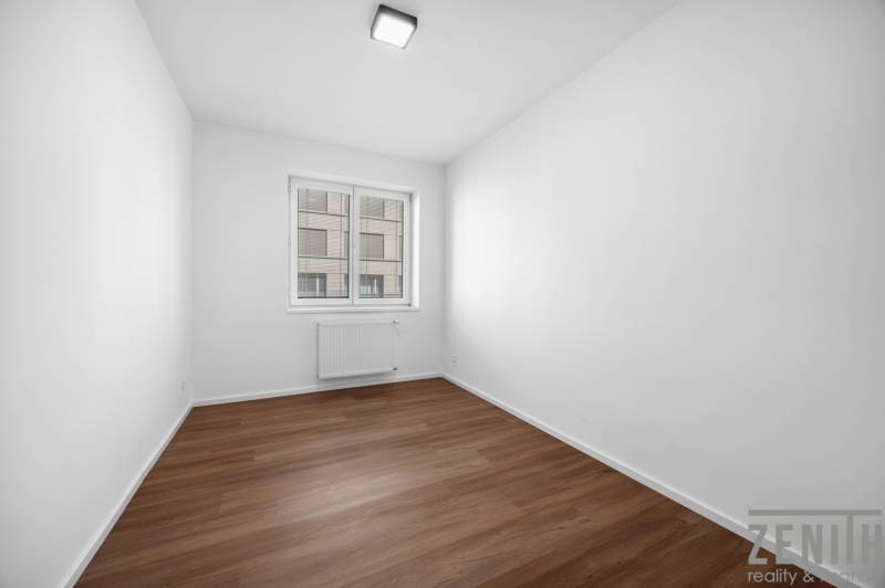 An empty room with a wooden floor and a window in a three-room apartment.