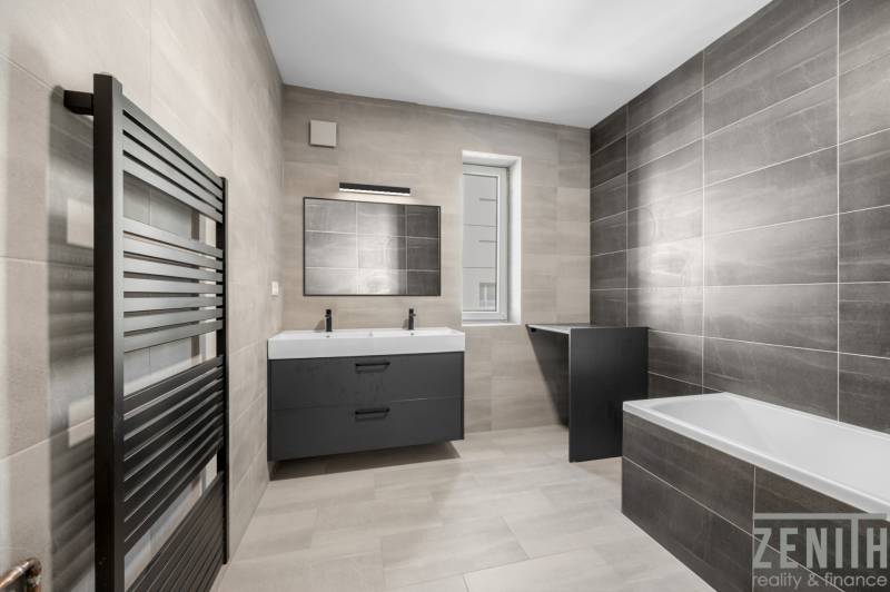 Spacious bathroom in a 3-room apartment with gray tiles, double sink, and bathtub.
