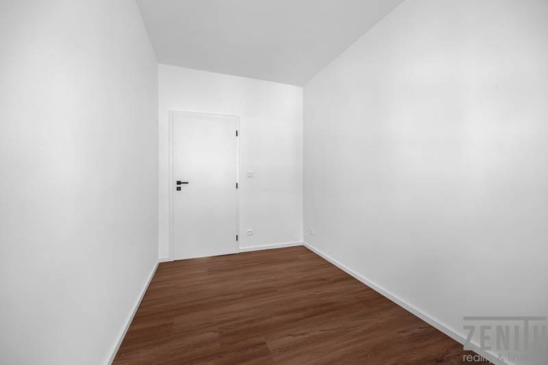 An empty room with white walls and wooden flooring in a 3-room apartment.