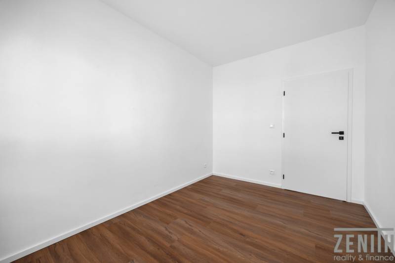 An empty room with wooden flooring and white walls in a 3-room apartment.