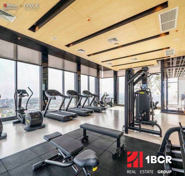 A gym with a view, equipped with treadmills and exercise machines. Apartment construction.