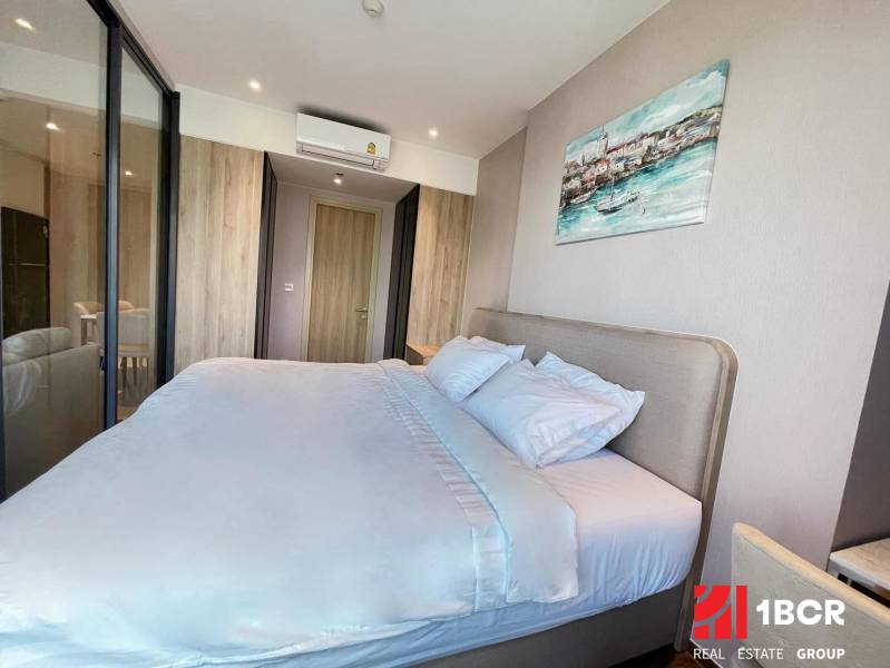 A bright bedroom with a large bed in a two-room apartment, surrounded by wooden details.